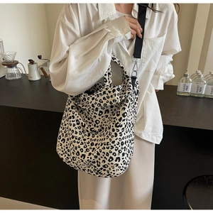Dettaglio della borsa tote in tela leopardata con tracolla larga in un caffè