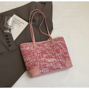 Gros plan du sac cabas rose tissé avec coins en cuir et plaque de logo de marque en métal