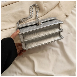 Detailed view of silver quilted crossbody bag with dual-compartment structure and metal clasp