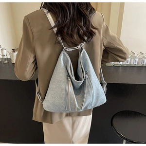 Detailed view of light blue denim tote with silver zippers and grey adjustable straps