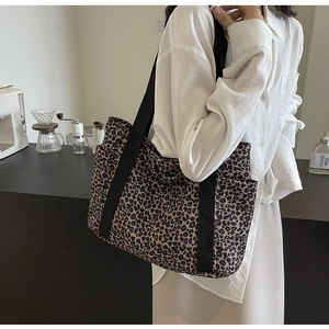 Primer plano de bolso tote de lona con estampado de leopardo y correas negras en un café