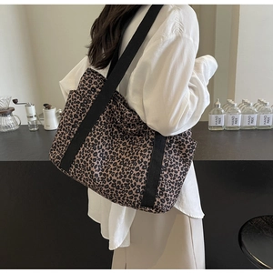 Vista detallada del bolso tote de lona con estampado de leopardo y correas negras anchas