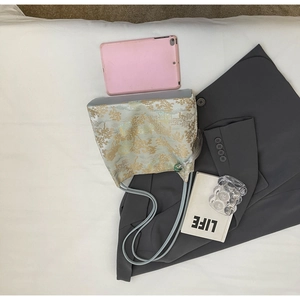 Flat lay of oriental embroidered tote bag with landscape pattern, tassel and silk straps