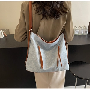 Detail of grey hobo bag with brown strap contrast and front zipper pockets