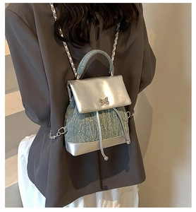Détail du sac à dos en denim bleu et argent avec perles et boucle papillon élégante