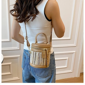 Detail of woven bucket bag with brown leather trim and golden zipper on shoulder