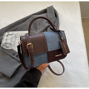 Dettaglio di cuciture a contrasto, pelle marrone e denim blu su questa mini borsa di moda
