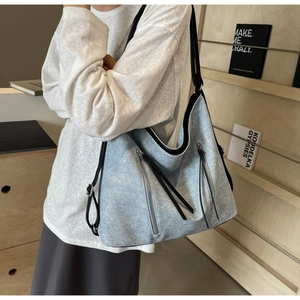Detailed texture of light blue denim tote bag with vertical zippers and black straps