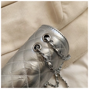 Detailed macro view of silver quilted bucket bag with metallic chain and stitching