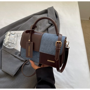 Dettaglio della borsa piccola color-block con denim blu e texture in pelle marrone