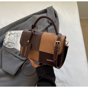 Dettaglio di borsa a mano bicolore in pelle liscia e pelle scamosciata con ciondolo moda