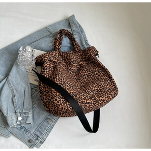 Vista piatta di una borsa tote in tela leopardata con tracolla larga e oggetti moda