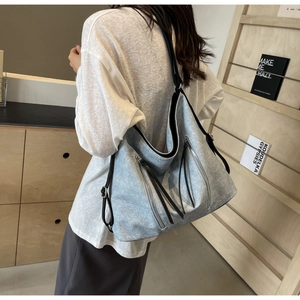 Detailed view of light gray tote bag with four zippered pockets and long leather pullers