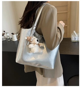 Detail of silver metallic tote bag featuring a cute plush bear charm with Lovely tag