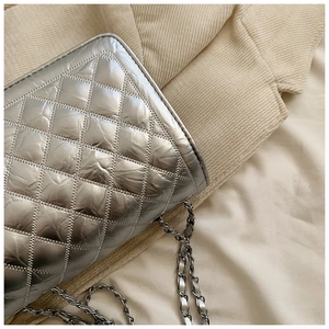 Macro shot of silver metallic quilted leather and intertwined chain strap detail