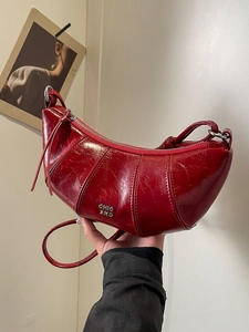 Sac croissant en cuir huilé bordeaux avec texture plissée et logo métallique argenté