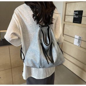 Detail of light gray vintage canvas backpack with vertical metal zippers and leather straps