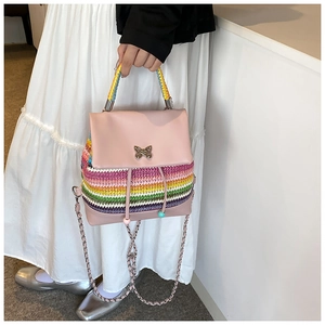 Détail du sac en cuir rose avec texture tressée arc-en-ciel et fermoir papillon