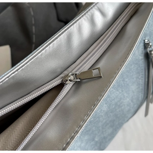 Close-up of silver tote bag showing zipper detail and herringbone textured lining
