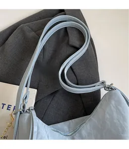 Détail du sac cabas bleu clair avec bandoulière lisse et décoration de chaîne dorée