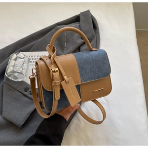 Dettaglio borsa a tracolla in pelle marrone e denim blu con targhetta moda