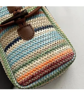 Close-up of colorful woven straw fabric with horn buckle and brown leather trim detailing