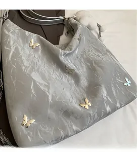 Dettaglio della borsa hobo argento metallizzato con rivetti a farfalla e catena