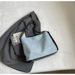 Flat lay of light blue denim texture tote bag with black leather reinforcement straps