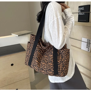 Detalle de bolso tote de lona con estampado de leopardo, correa ancha y bolsillo lateral