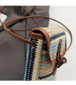 Detail of woven straw phone bag with colorful rainbow stripes and horn toggle closure