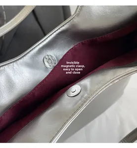 Macro shot of silver magnetic closure and burgundy lining on tote bag