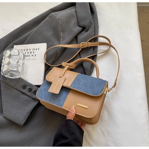 Dettaglio della borsa bicolore in pelle PU e denim con finiture dorate su sfondo fashion
