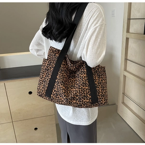Detalle de bolso tote de lona con estampado de leopardo y correas negras al hombro
