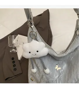 Ciondolo a nuvola di peluche con gambe a righe appeso a una borsa a tracolla grigia