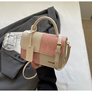 Dettaglio borsa a tracolla rosa e beige con fibbia dorata e ciondolo alla moda