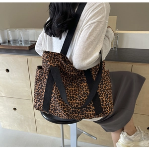 Bolso tote grande de lona con estampado de leopardo llevado por una modelo en un café
