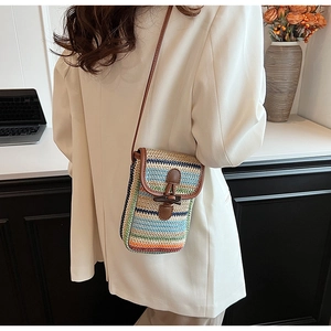 Close-up of rainbow striped straw phone bag with leather trim and wooden button