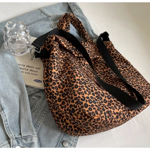 Dettaglio ravvicinato della borsa tote in tela leopardata su denim con fibbie in metallo