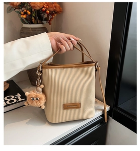 Detailed view of cream pleated bucket bag with brown trim and cute plush bear charm