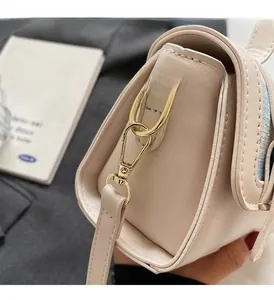Close-up of premium gold-toned metal hardware and lobster clasp on beige crossbody bag