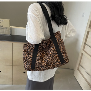 Detalle de las correas anchas de tejido negro de un bolso tote de lona con leopardo