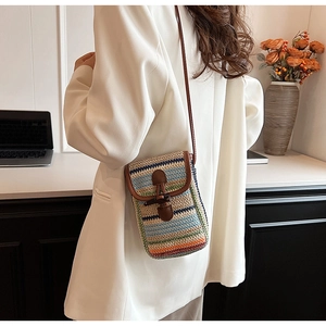 Detail of colorful rainbow woven straw phone bag featuring horn buckle and leather trim