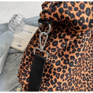 Dettaglio della borsa in tela leopardata con chiusura a moschettone argento e tracolla nera