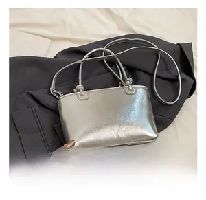Detail shot of silver bucket bag with pleated texture on a grey suit jacket