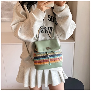 Détail du mini sac à dos montrant le tissage rayé et le fermoir papillon métallique