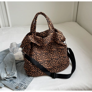 Dettaglio della borsa tote in tela leopardata con tracolla regolabile nera su sfondo bianco