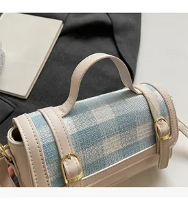 Close-up of blue plaid fabric handbag with beige leather straps and gold metal buckle