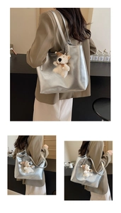 Detail of silver metallic tote bag with sleek finish and cute white plush bear pendant