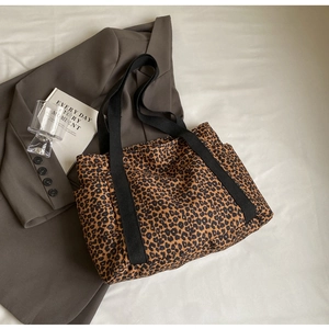 Detalle de bolso tote de lona con estampado de leopardo, bolsillo lateral y asa negra