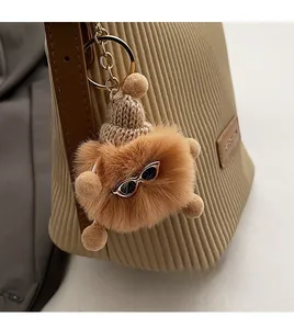 Detailed view of a brown plush cartoon charm with a mini hat on a pleated crossbody bag
